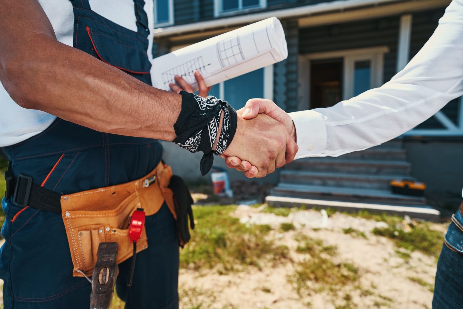Contractor and homeowner shaking hands outside a house