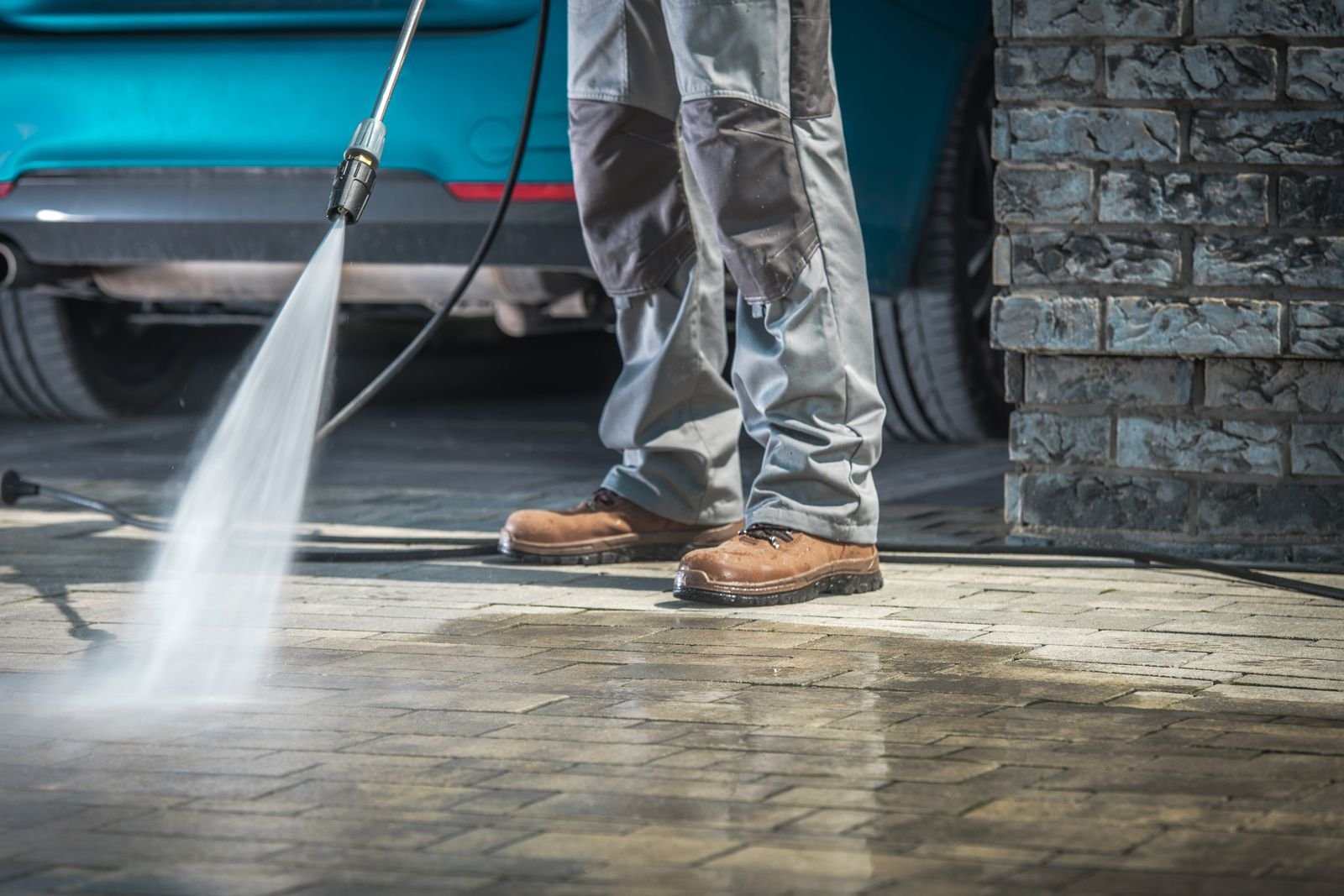 Brick paver driveway being washed beside a vehicle