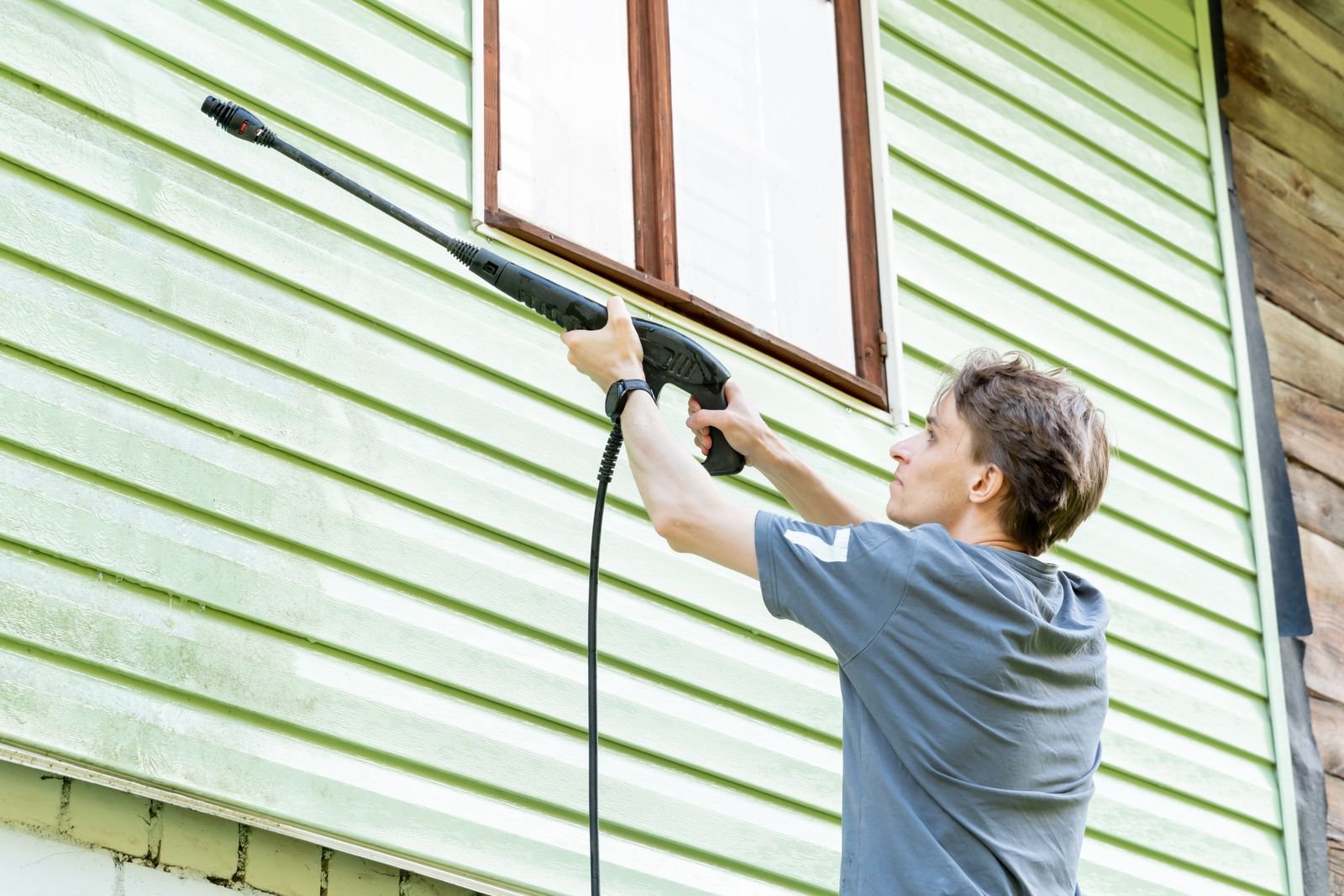 Soft washing green siding on a Greenville house
