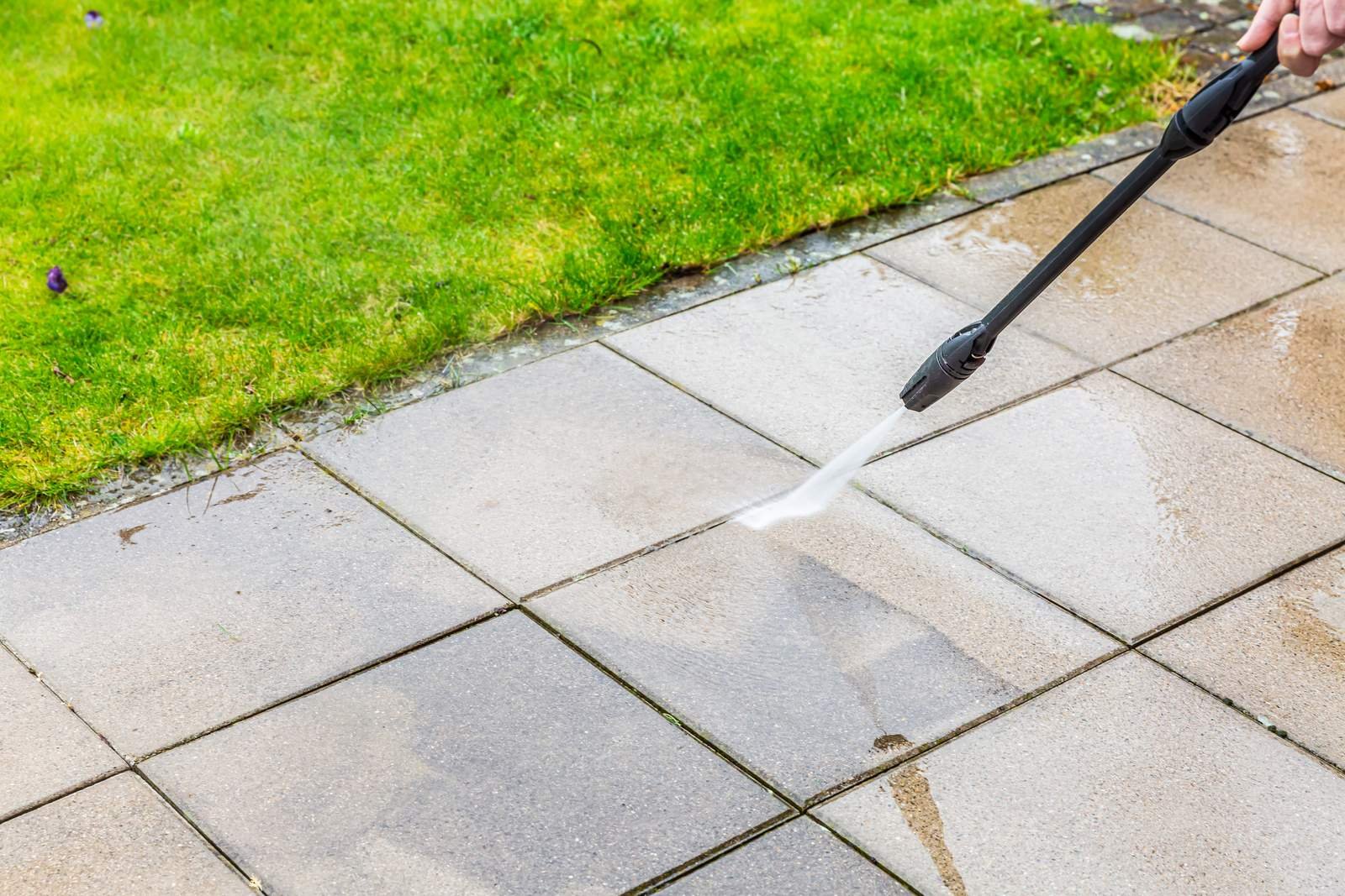 Terrace slabs being cleaned beside a lawn